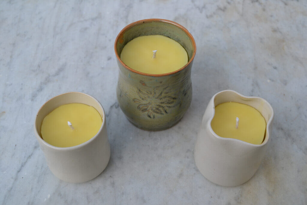 Set of the beeswax candles in ceramic vessels