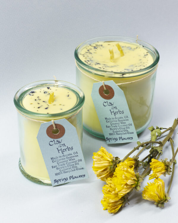 large and small Spring Flowers candles with a light blue backdrop and a small bunch of yellow flowers